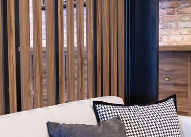 Interior moderno de The Beard Co. en Santiago De Querétaro, Querétaro, MX, con paredes de madera y cojines elegantes.