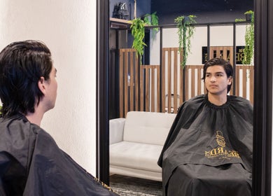 Cliente en The Beard Co., Santiago De Querétaro, Querétaro, MX, observando su reflexión en espejo del salón.