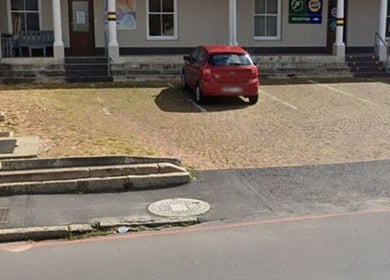 Entrance of Wellue Beauty in Paarl, Western Cape, ZA, featuring a red car in a peaceful parking area.