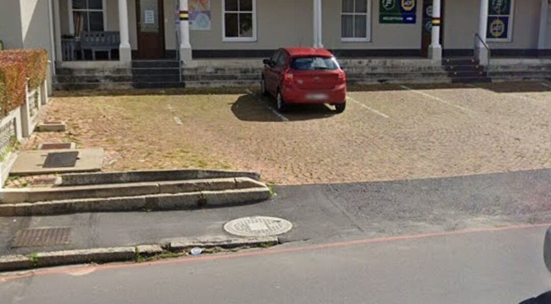 Entrance of Wellue Beauty in Paarl, Western Cape, ZA, featuring a red car in a peaceful parking area.