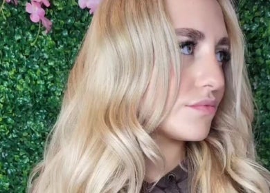 Elegant blonde waves styled at Carly Styles @ Artistic Hair Co., Bristol, England, GB with floral backdrop.