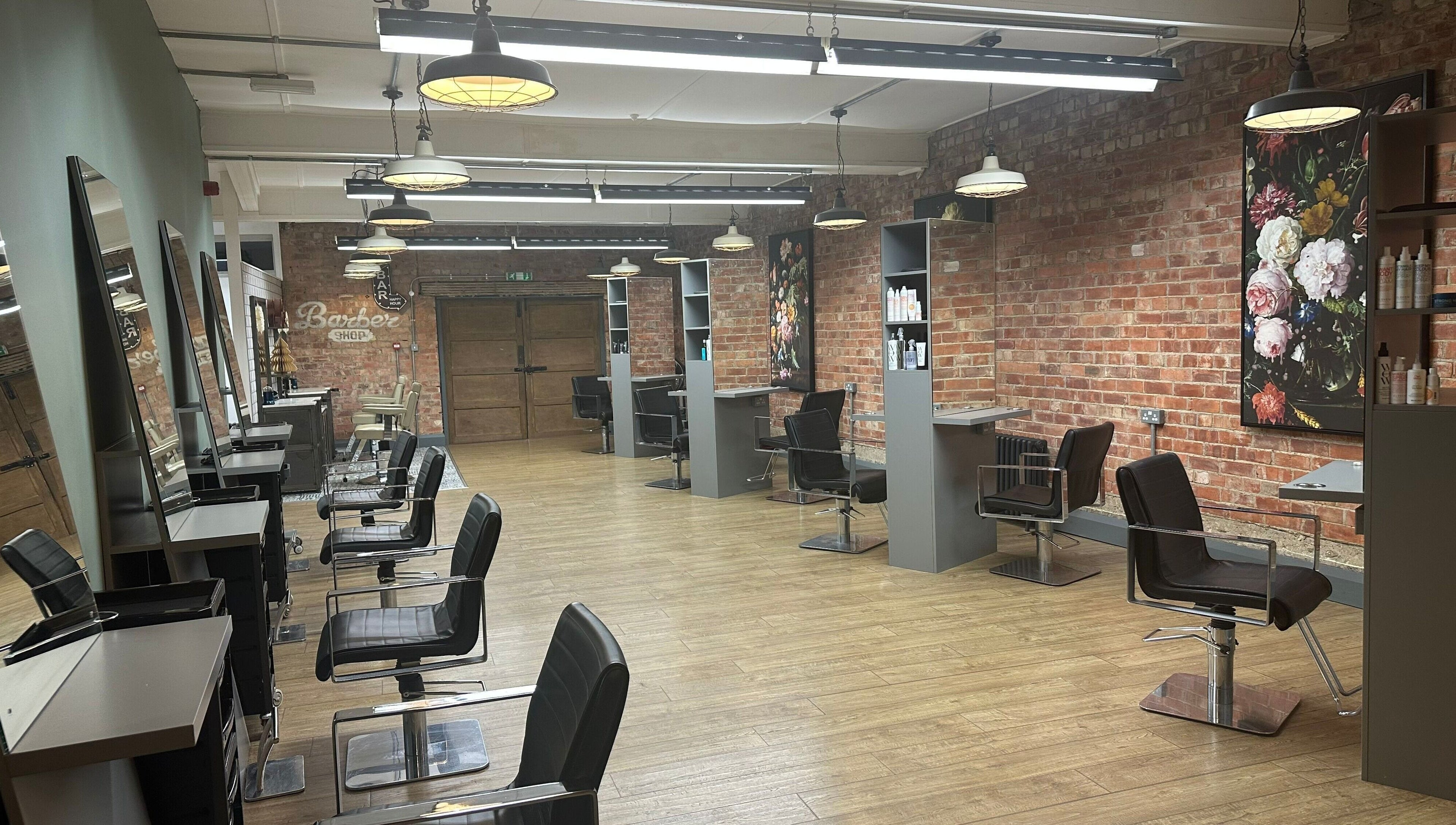 So & So Hairdressing in Whitley Bay, England, GB features chic salon chairs, mirrors, and a brick accent wall.