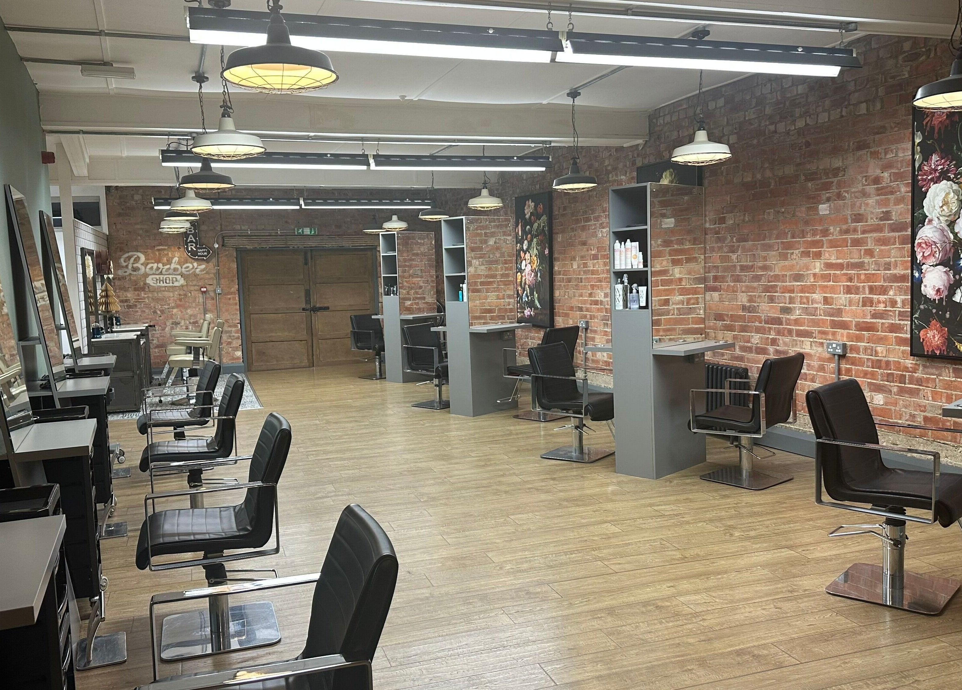 So & So Hairdressing in Whitley Bay, England, GB features chic salon chairs, mirrors, and a brick accent wall.