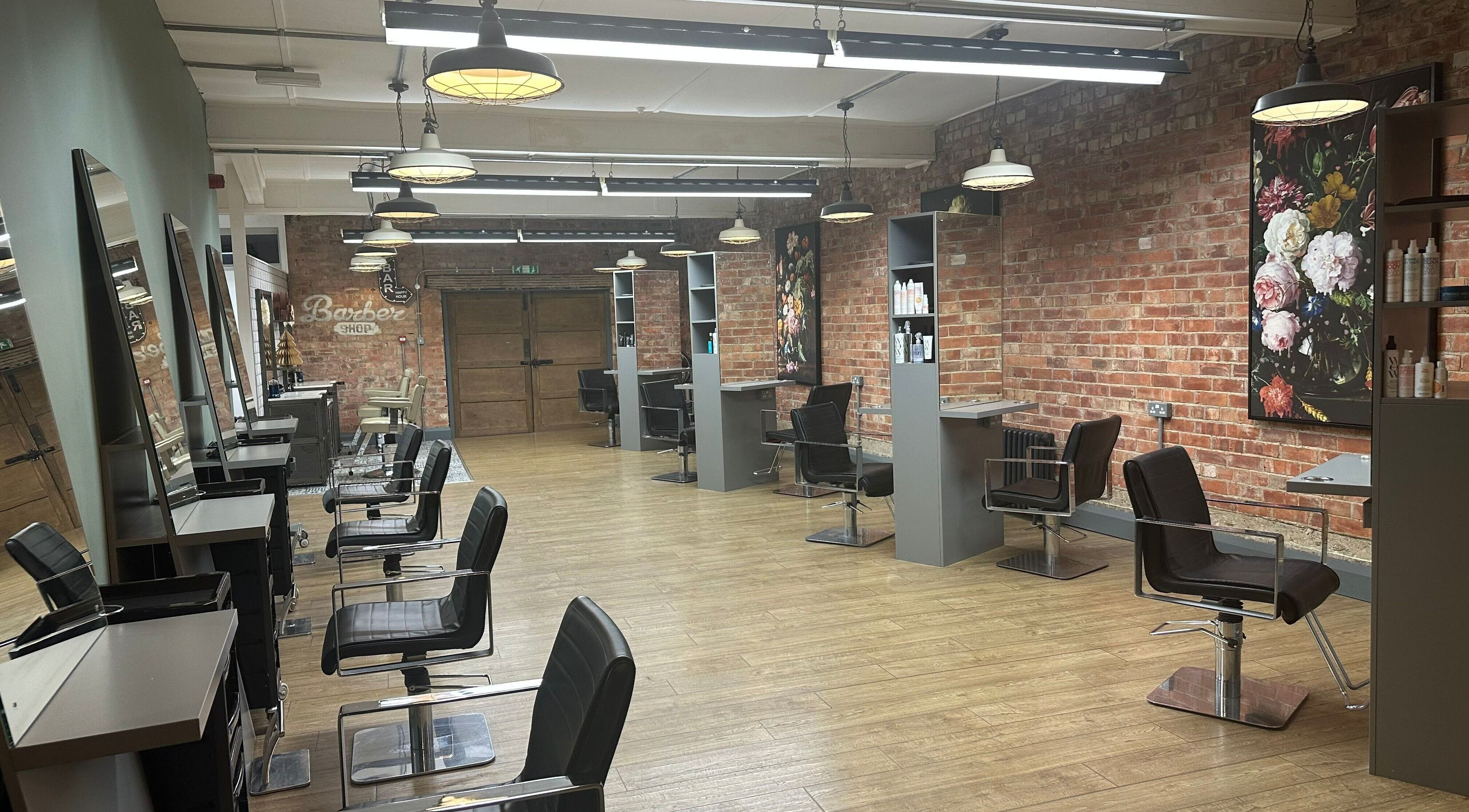 So & So Hairdressing in Whitley Bay, England, GB features chic salon chairs, mirrors, and a brick accent wall.