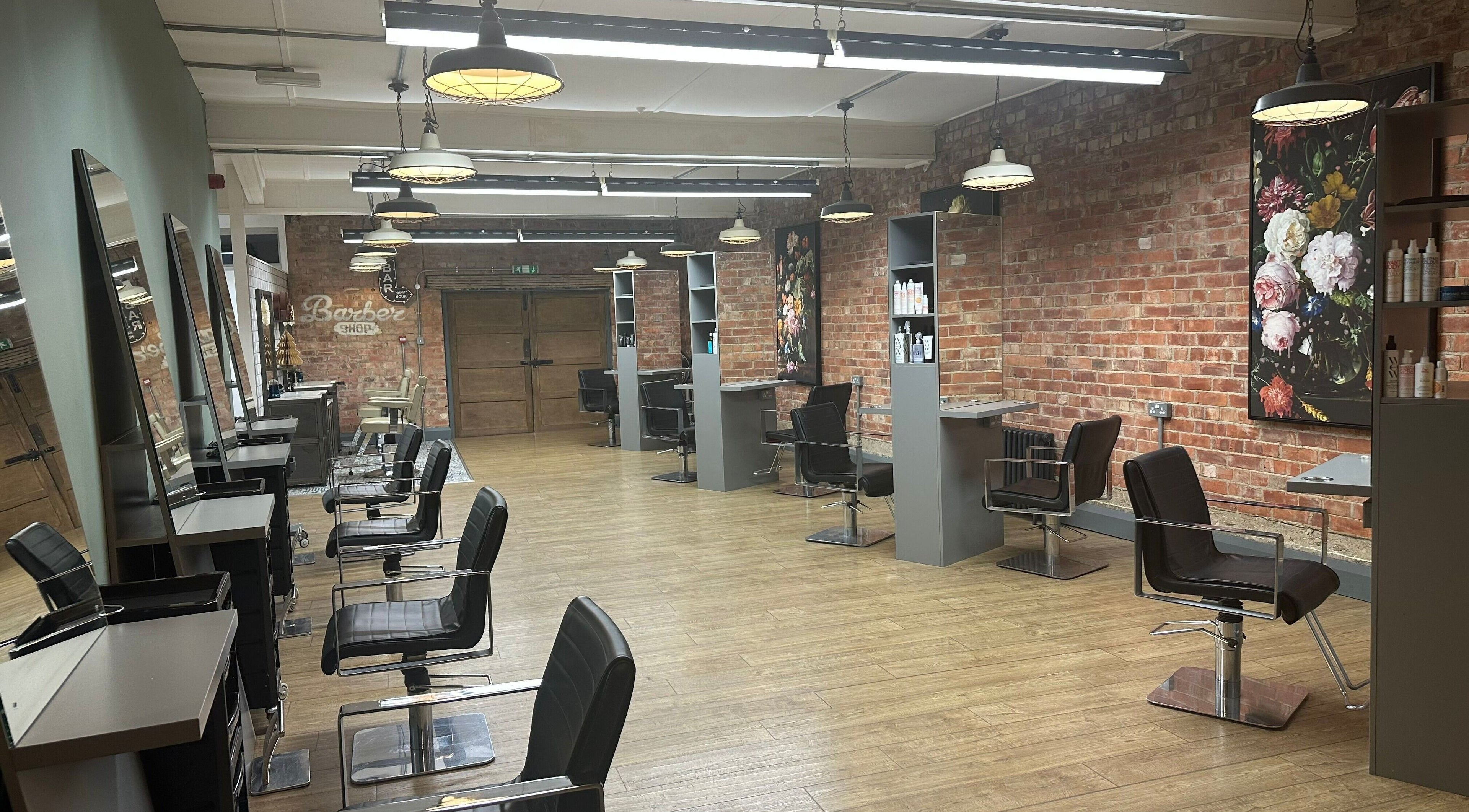So & So Hairdressing in Whitley Bay, England, GB features chic salon chairs, mirrors, and a brick accent wall.