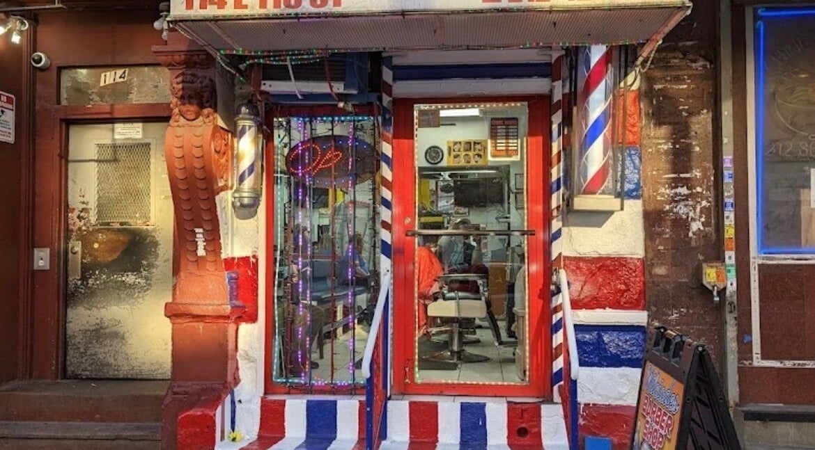 BarberingRicky storefront displaying vibrant barber pole and neon signs in New York, New York, US.