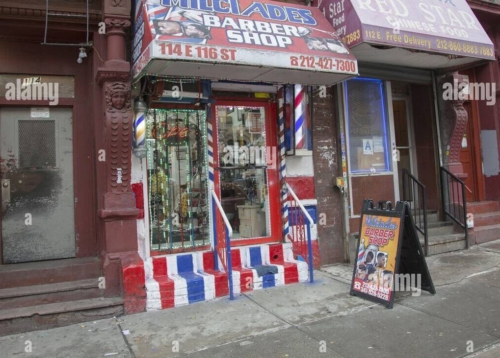 Exterior of BarberingRicky, a vibrant barber shop in New York, New York, US, showcasing classic barber pole design.
