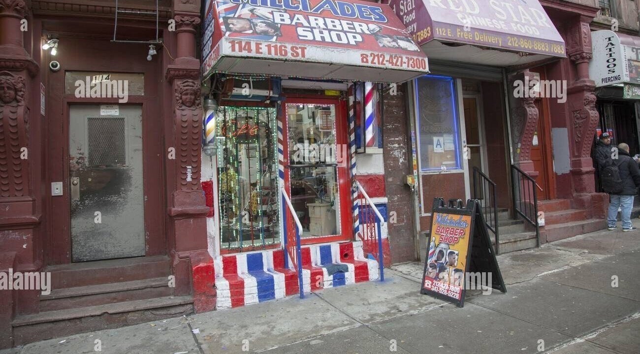Front of BarberingRicky located in New York, New York, US. Colorful barber pole design and street signage.