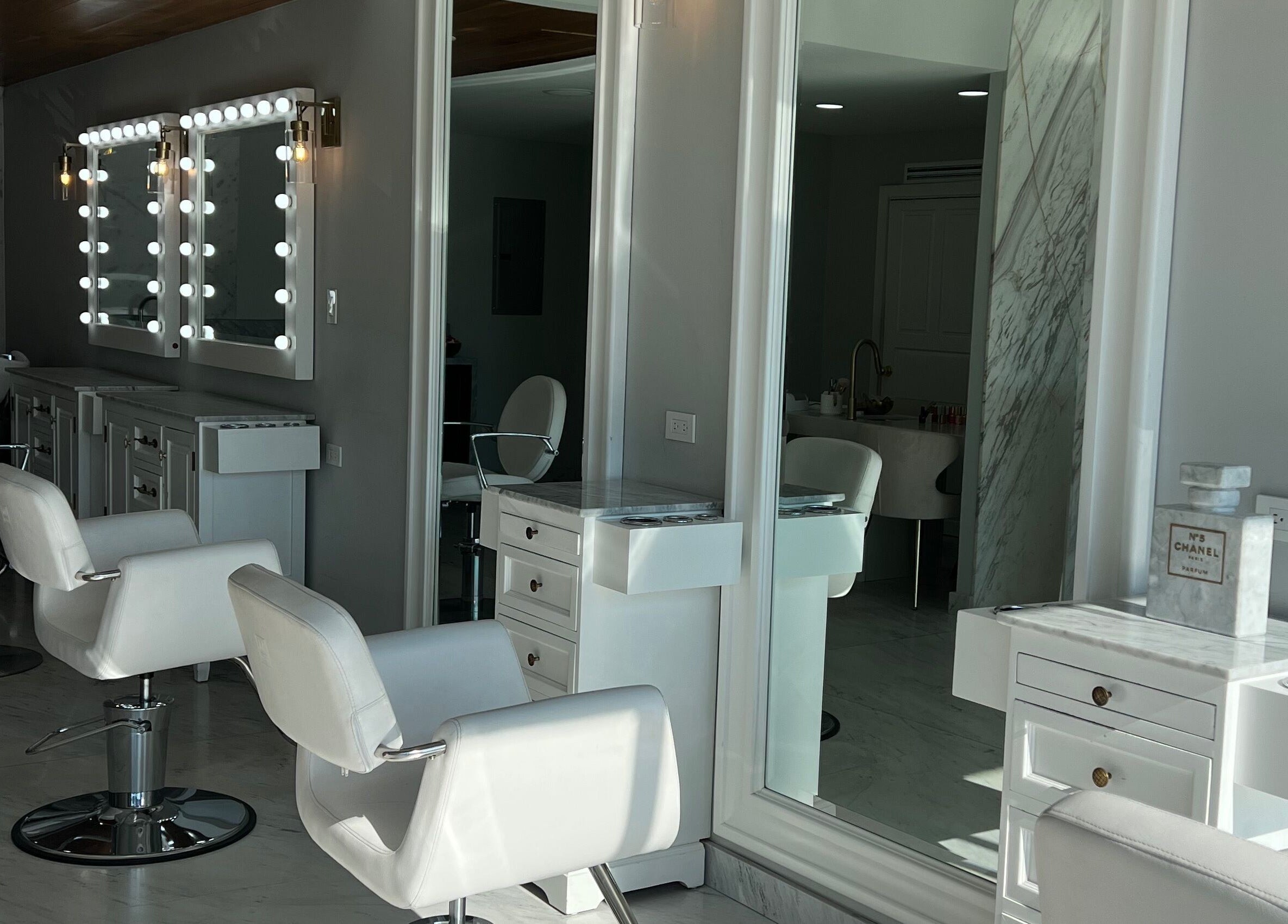 Interiores elegantes de VICA STUDIO, Chihuahua, Chihuahua, MX con sillas blancas y espejos iluminados.