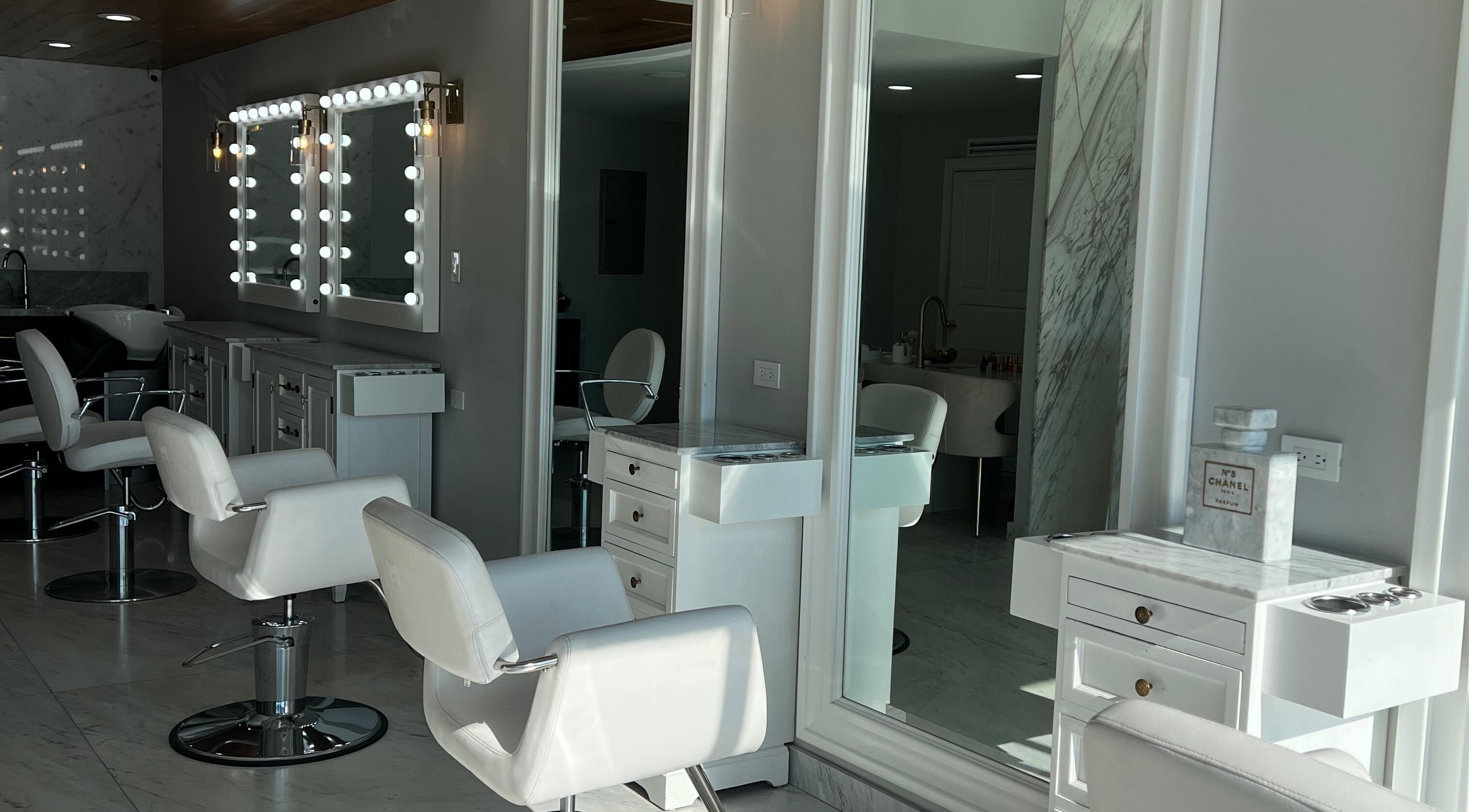 Interiores elegantes de VICA STUDIO, Chihuahua, Chihuahua, MX con sillas blancas y espejos iluminados.