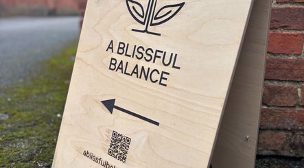 Wooden sign for A Blissful Balance points visitors in Wellesbourne, England, GB.