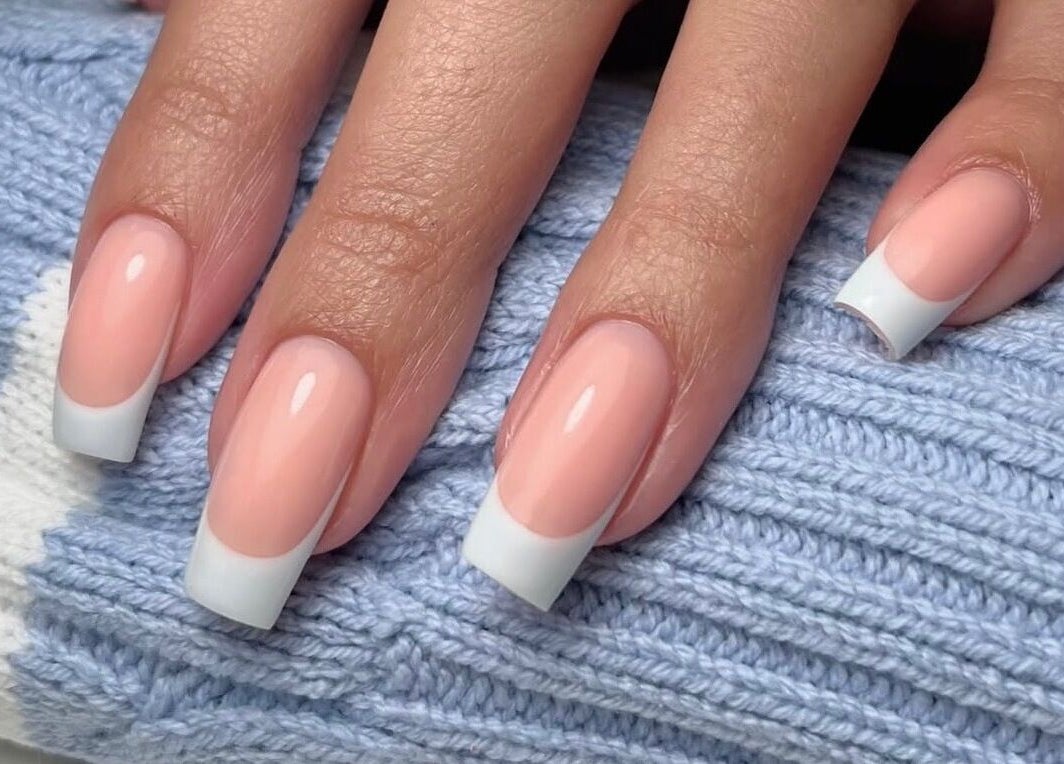 Elegant French manicure by Painted By Lauryn in Hayes, England, GB, showcasing glossy nails on a blue knit.