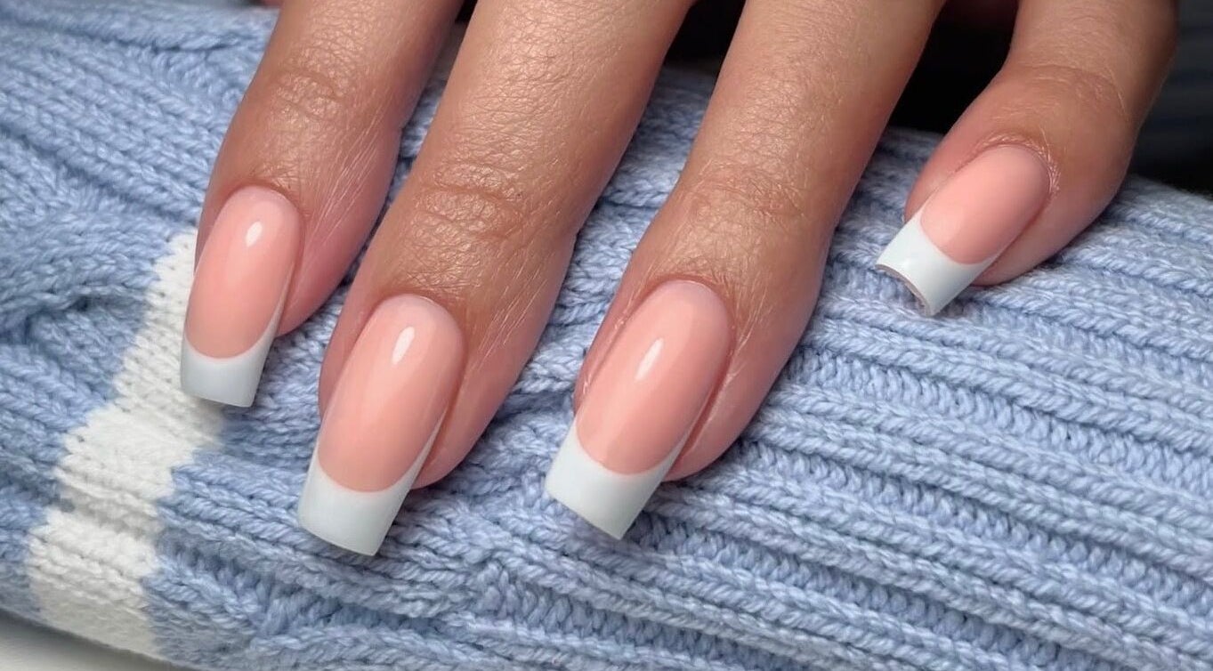 Elegant French manicure by Painted By Lauryn in Hayes, England, GB, showcasing glossy nails on a blue knit.