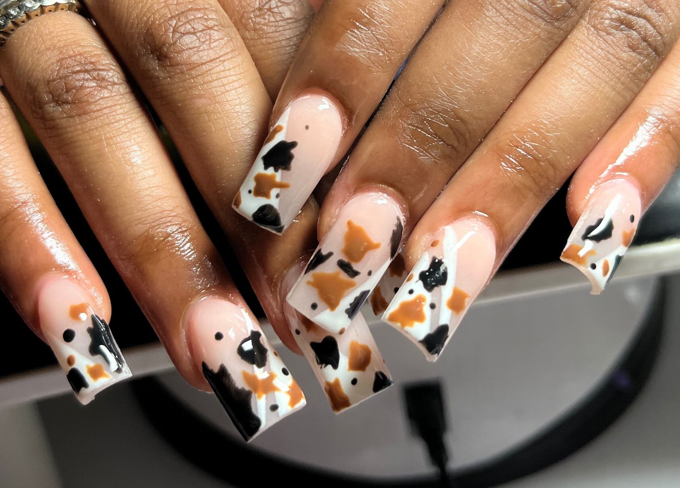 Creative nail art at Visage VERITAS in Troy, New York, US featuring unique black and orange patterns.