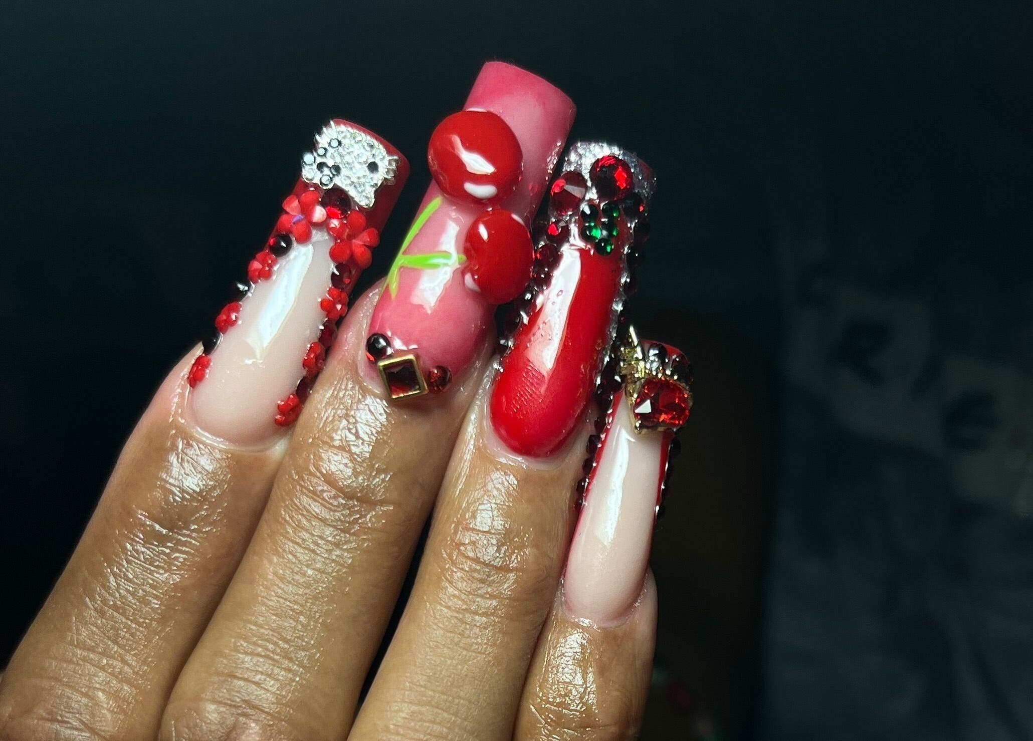 Stunning red gemstone nails at Visage VERITAS, Troy, New York, US, showcasing intricate cherry designs.