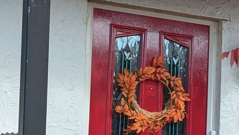 Elegant red door with autumn wreath at Sarah Harris Tattoos, Bishop's Stortford, England, GB.