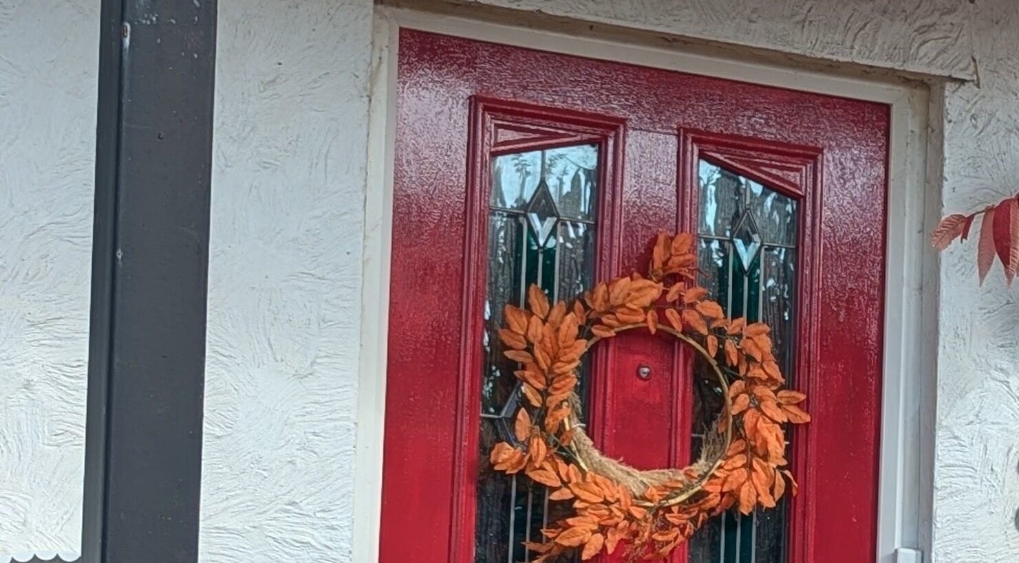 Elegant red door with autumn wreath at Sarah Harris Tattoos, Bishop's Stortford, England, GB.