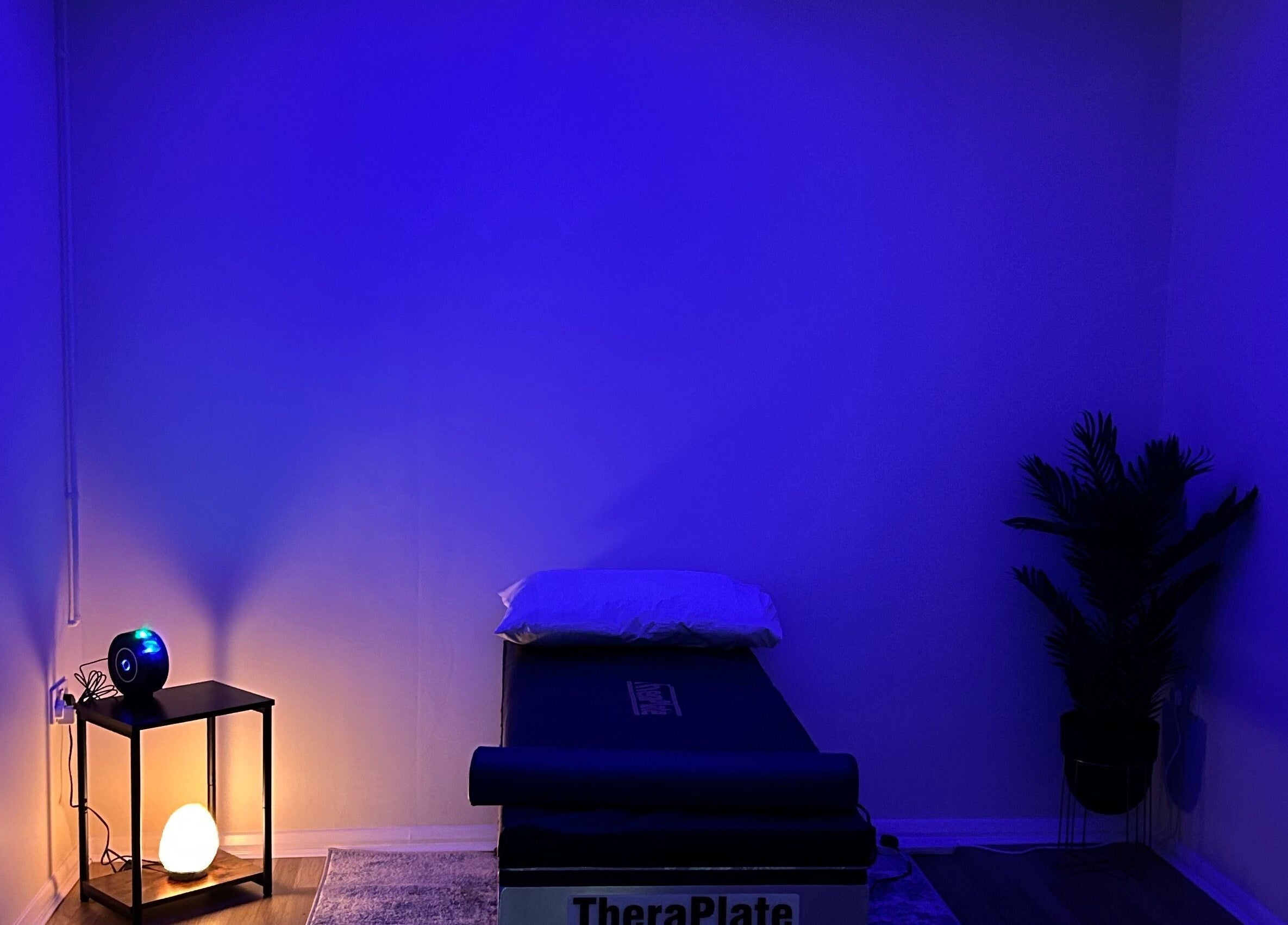 Tranquil wellness room at TheraPlate Kirton, Kirton, England, GB with soft blue lighting and a relaxation table.