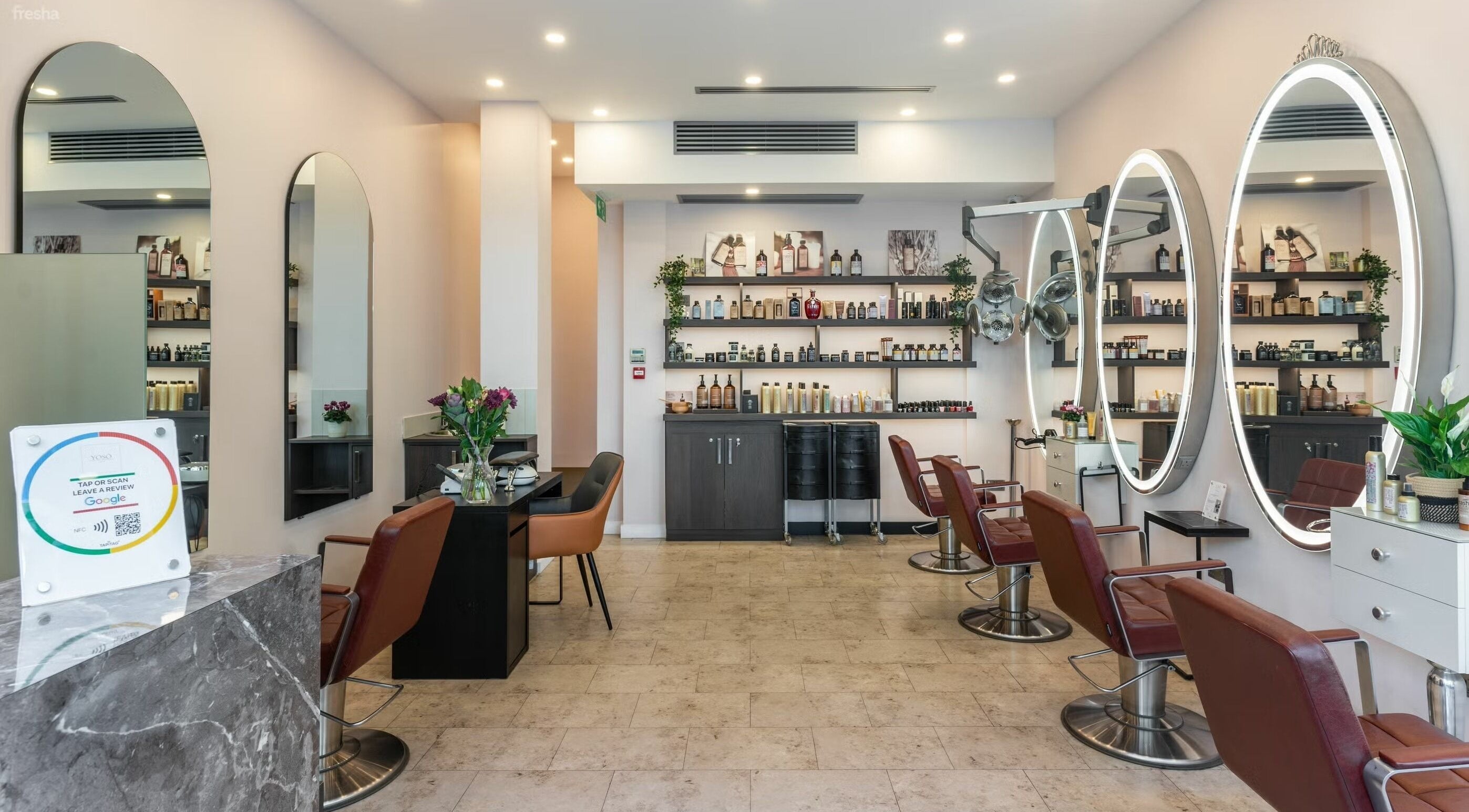 Chic salon setup at YASİ Hair & Beauty, London, England, GB with stylish chairs and illuminated mirrors.