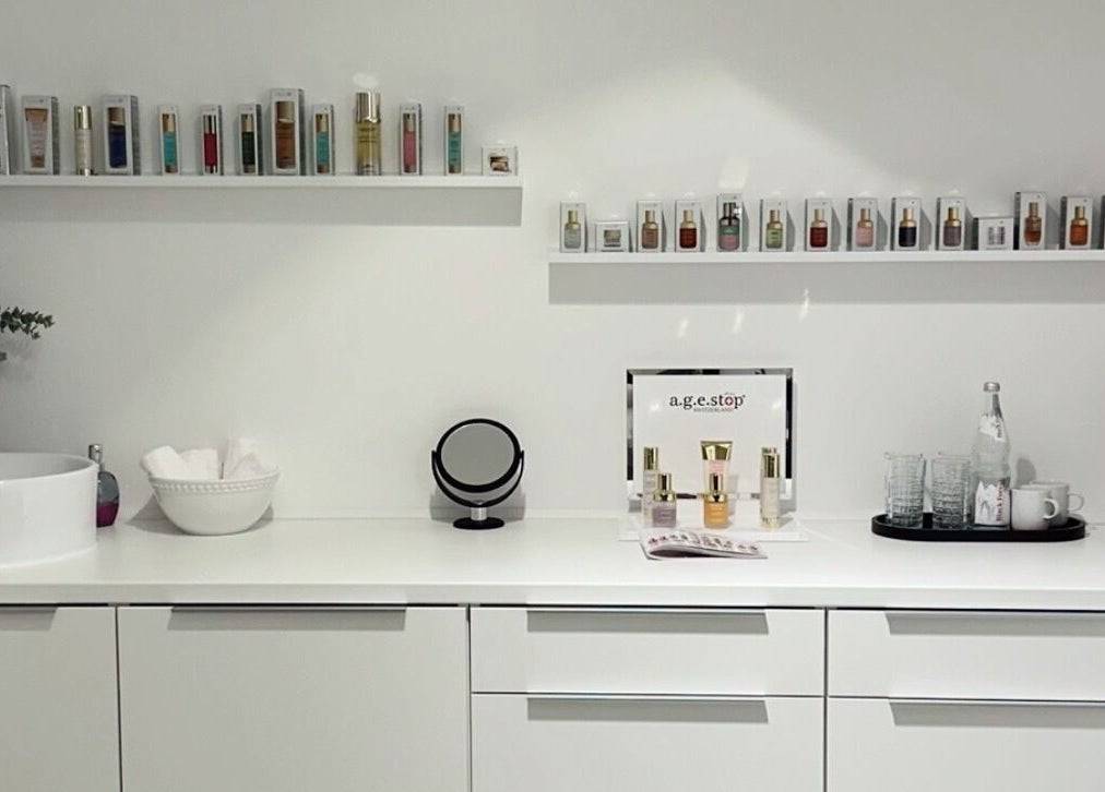 Innenansicht von Age-Stop Studio in Düsseldorf, Nordrhein-westfalen. Moderne weiße Einrichtung mit Schönheitsprodukten.