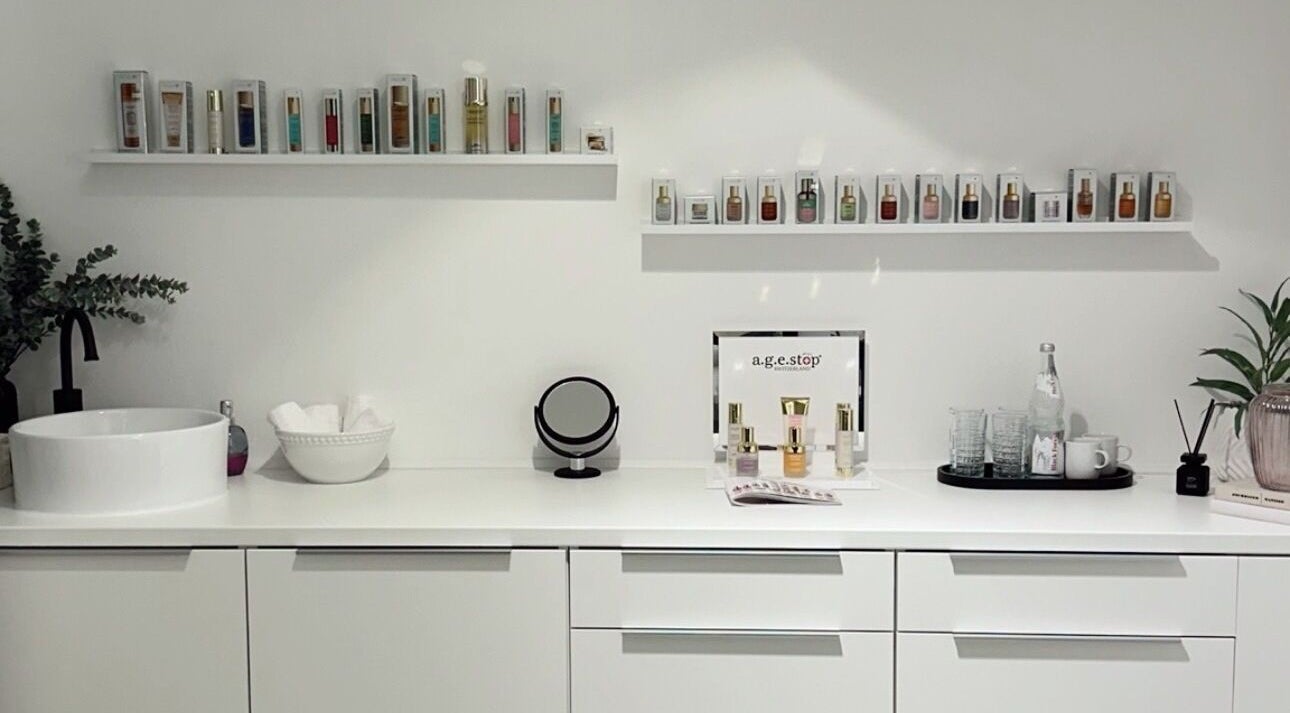 Innenansicht von Age-Stop Studio in Düsseldorf, Nordrhein-westfalen. Moderne weiße Einrichtung mit Schönheitsprodukten.