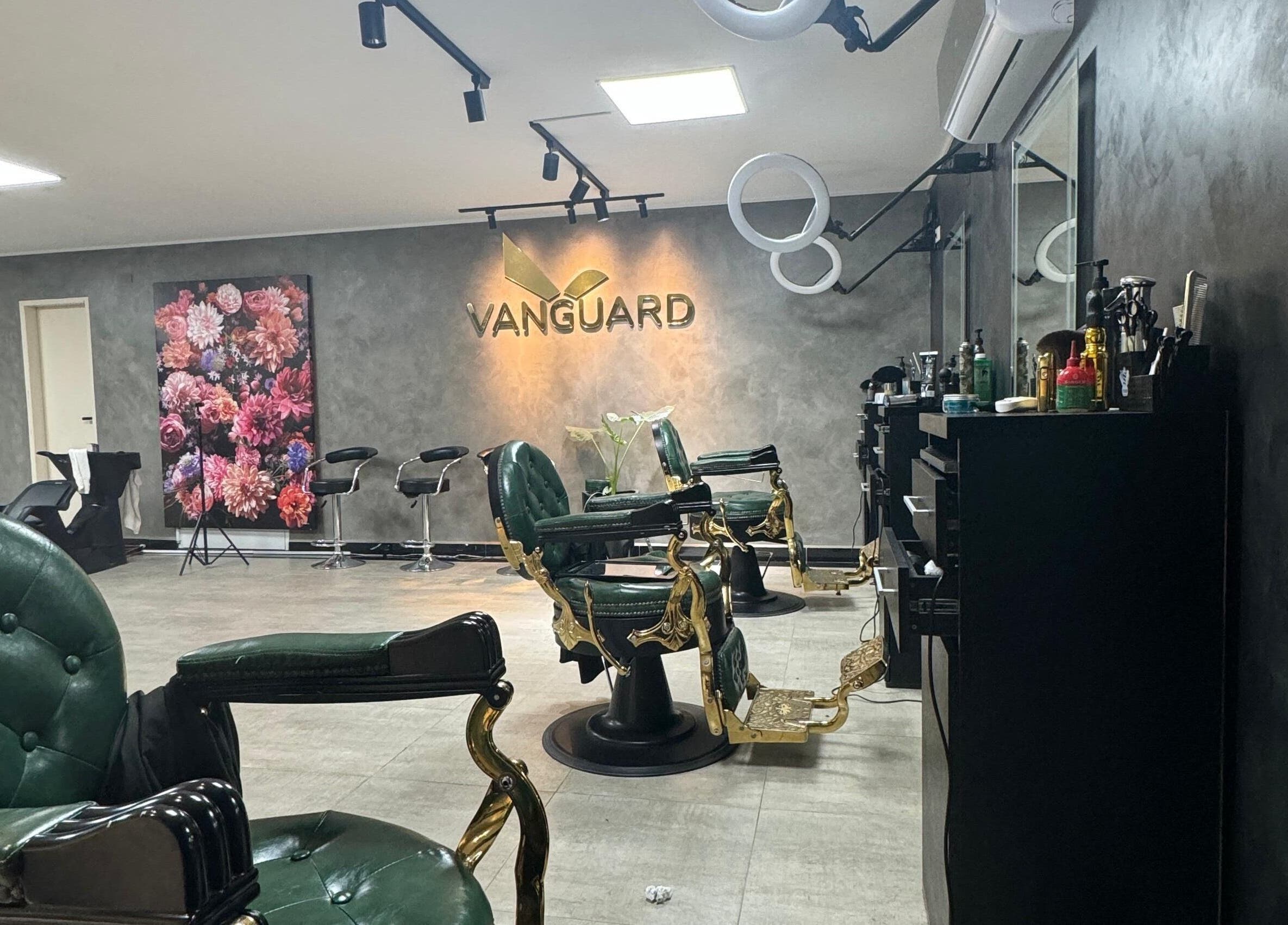 Interior elegante de VANGUARD en Santa Cruz De La Sierra, con sillas de barbero verdes y decoración floral.