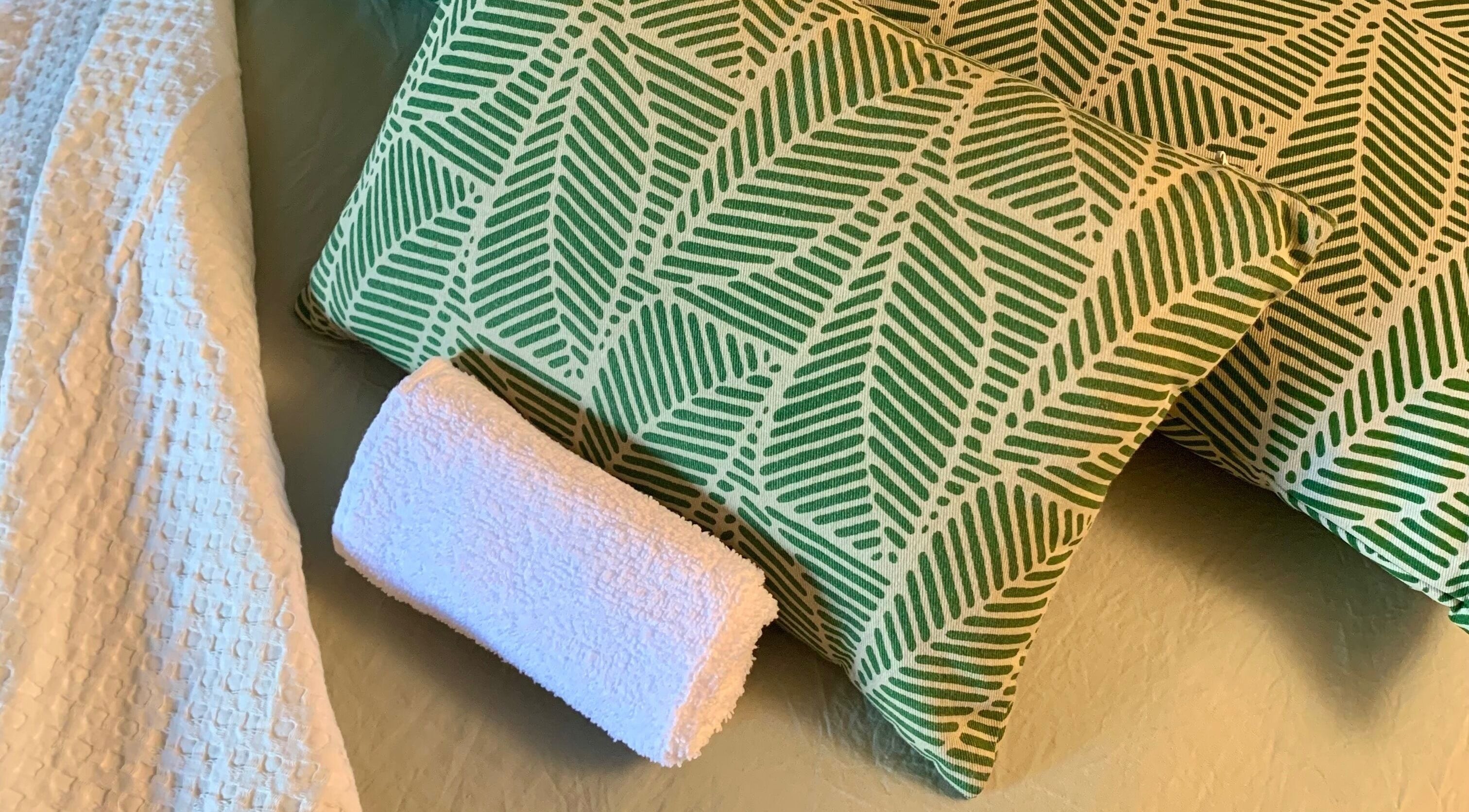 Coussins verts à motif feuille et serviette blanche à La cabine, Brive-la-Gaillarde, Nouvelle-Aquitaine, FR.