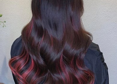Elegant wavy hairstyle with red highlights at Finesse Beauty & Hair Salon, Newcastle upon Tyne, England, GB.