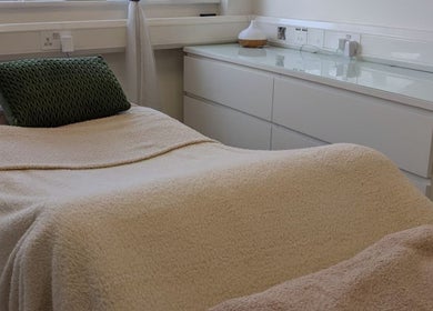 Cozy treatment room at Kintsugi Beauty & Holistics in Newton Abbot, England, GB, with a plush bed and soft lighting.