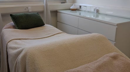 Cozy treatment room at Kintsugi Beauty & Holistics in Newton Abbot, England, GB, with a plush bed and soft lighting.