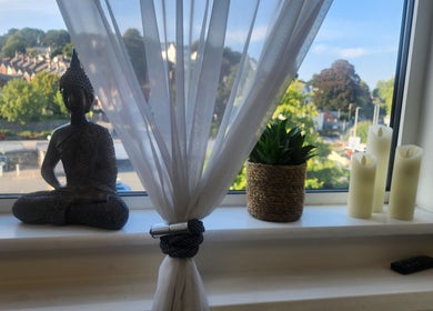 Peaceful window view at Kintsugi Beauty & Holistics, Newton Abbot, England, GB with Buddha statue and candles.