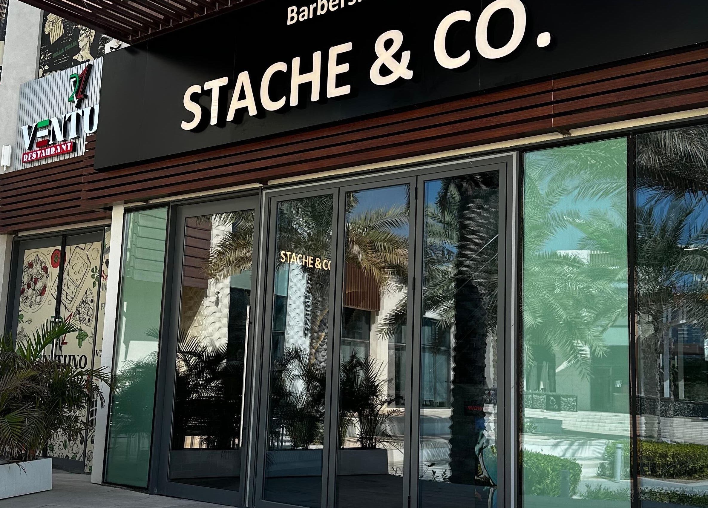 Stache & Co. Barbershop entrance, Reem Central Park, Abu Dhabi, AE with modern facade and palm tree reflection.