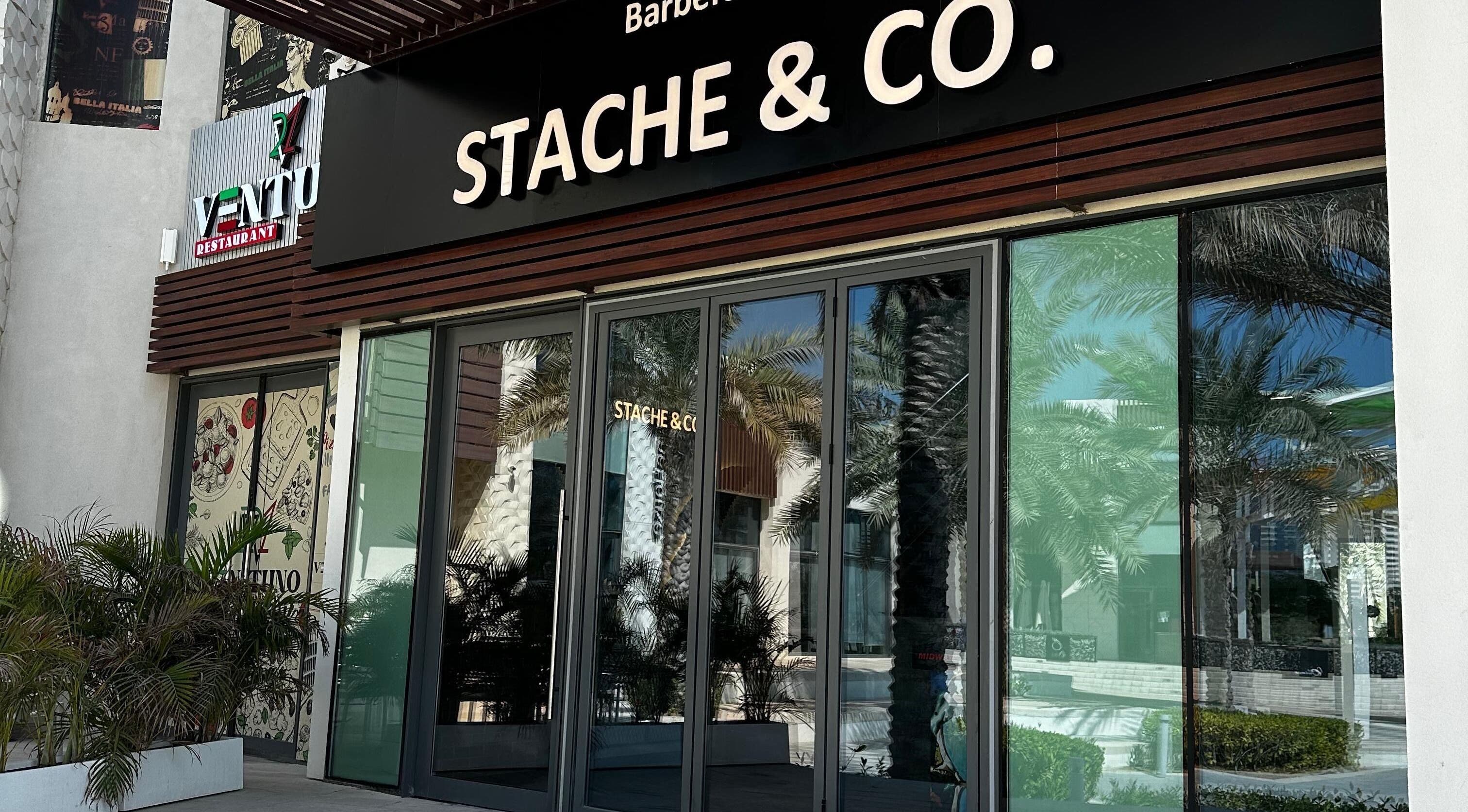 Stache & Co. Barbershop entrance, Reem Central Park, Abu Dhabi, AE with modern facade and palm tree reflection.