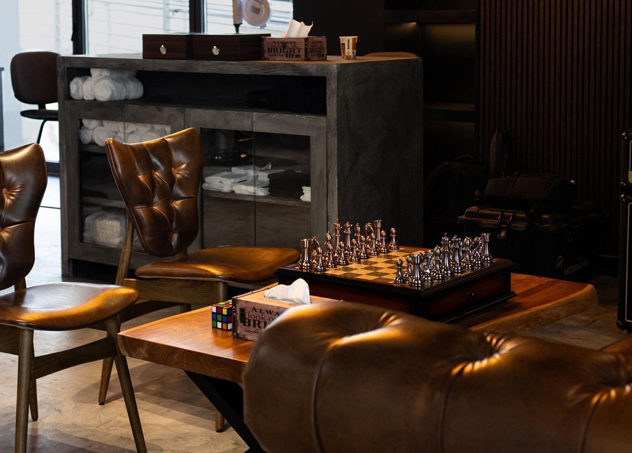 Cozy lounge area at Stache & Co. Barbershop - Reem Central Park, Abu Dhabi, featuring chess set and leather chairs.