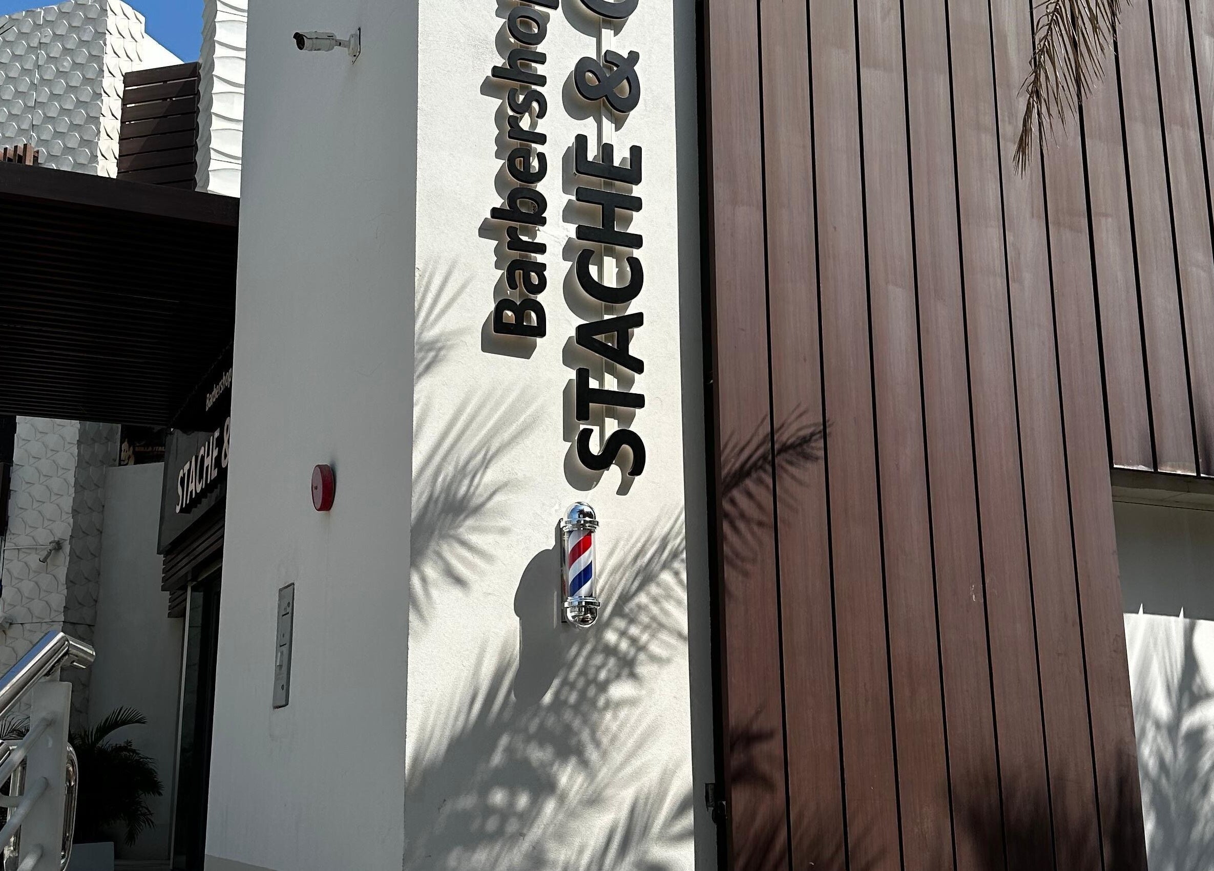 Front of Stache & Co. Barbershop - Reem Central Park, Abu Dhabi, with logo on modern exterior.