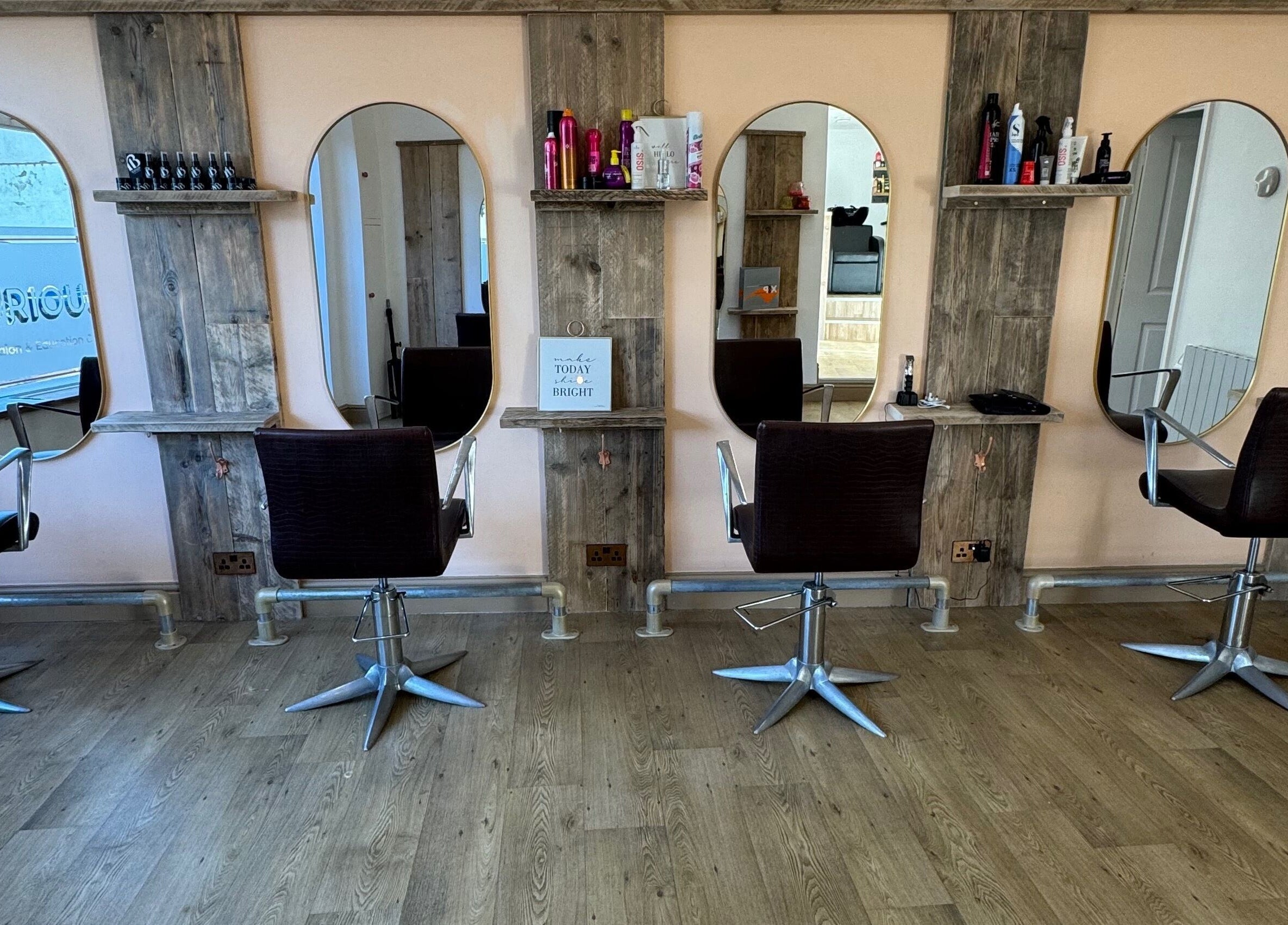 The Curious Stylist interior view in Bovey Tracey, England, GB showing four styling chairs and modern mirrors.