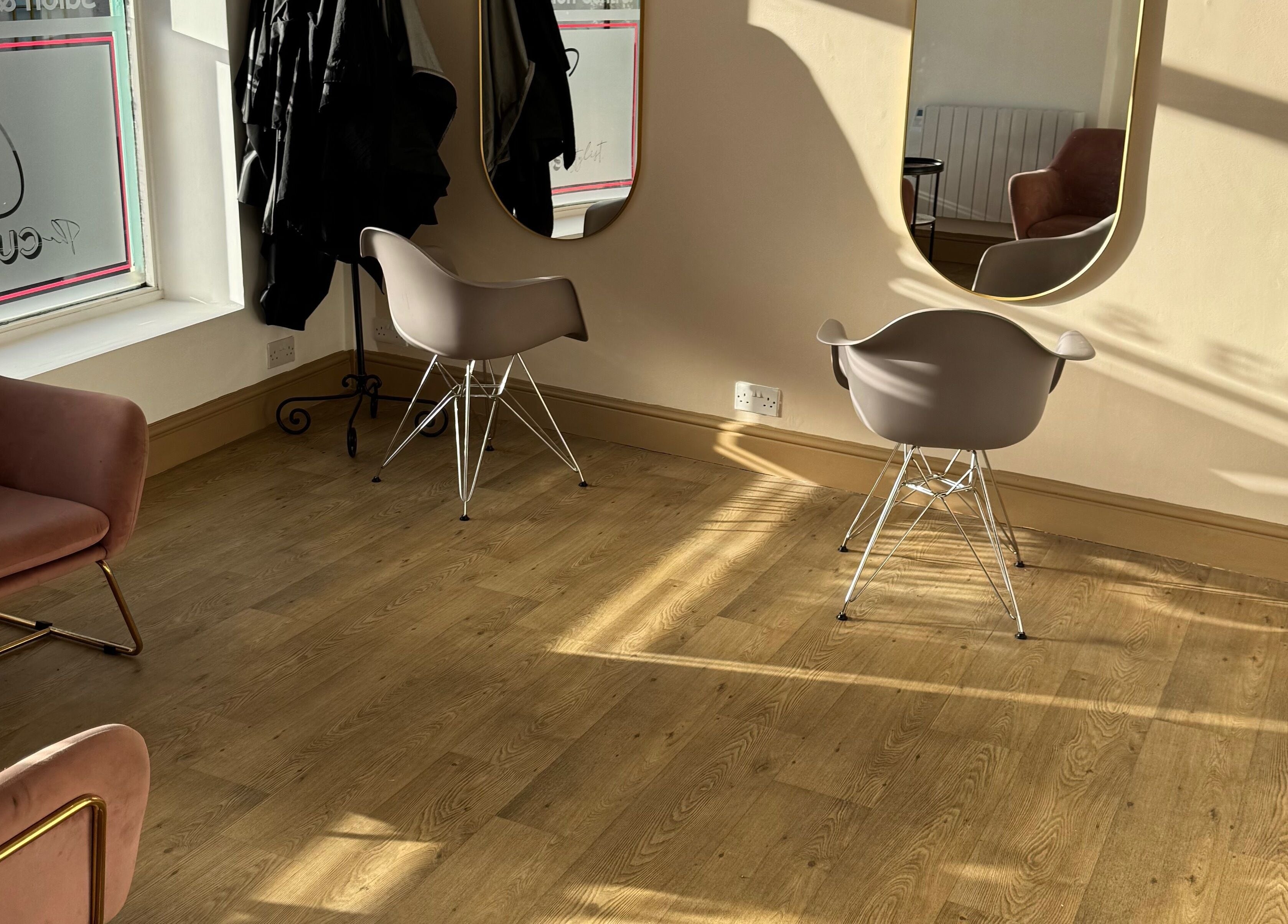 Inviting interior of The Curious Stylist in Bovey Tracey, England. Modern chairs and mirrors bask in warm sunlight.