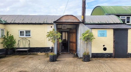 Front entrance of Balance and Heal, Royston, England with rustic decor inviting visitors inside.