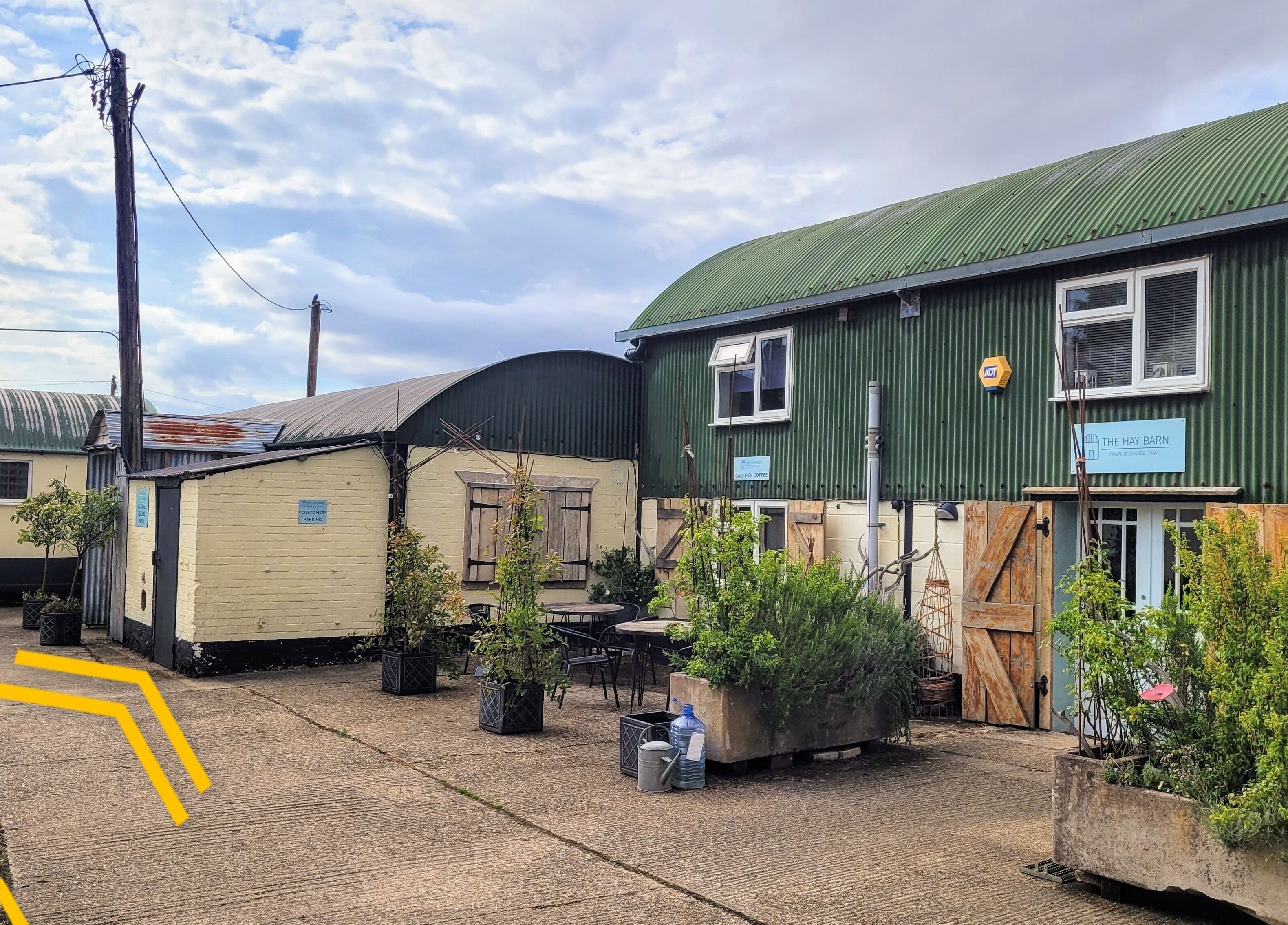 Exterior view of Balance and Heal at Royston, England, GB with green corrugated roof and courtyard plants.