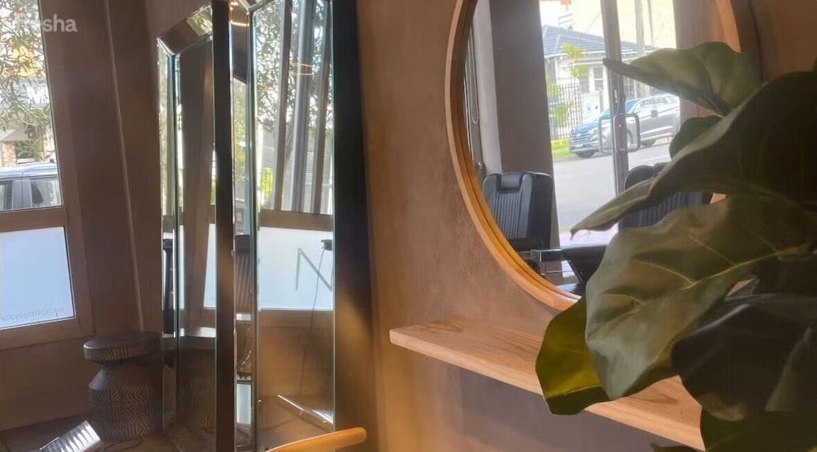 Chic interior of Nikola Krstev Salon, Wollongong, New South Wales, AU with large round mirror and green plant.