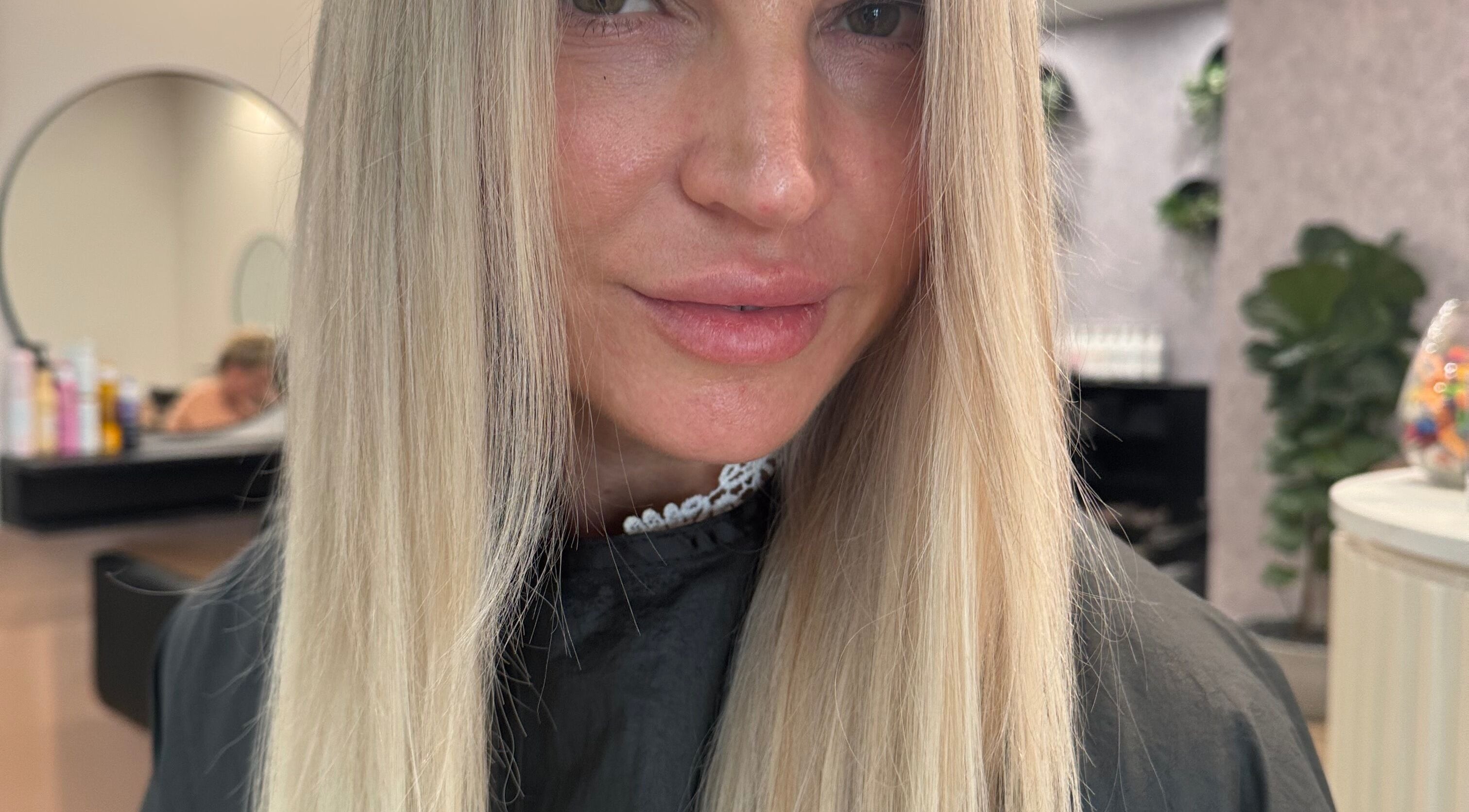 Woman with sleek blonde hair at Avenlee Hair Artistry, Currambine, Western Australia, AU. Modern salon setting.