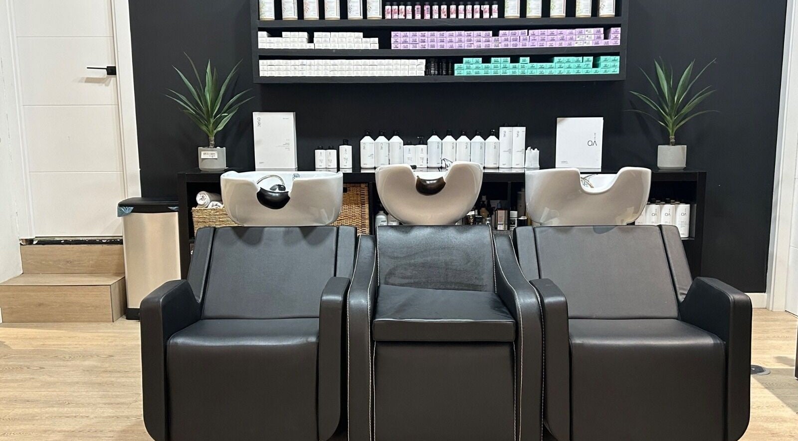 Zona de lavado moderna en Art & Care Beauty Lab, Vigo, ES, con sillas negras y productos profesionales.