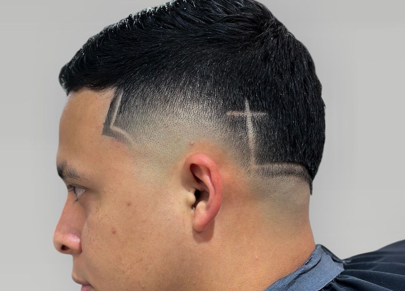 Stylish haircut at Charro Barber, Montebello, California, US, featuring creative shaved line design.