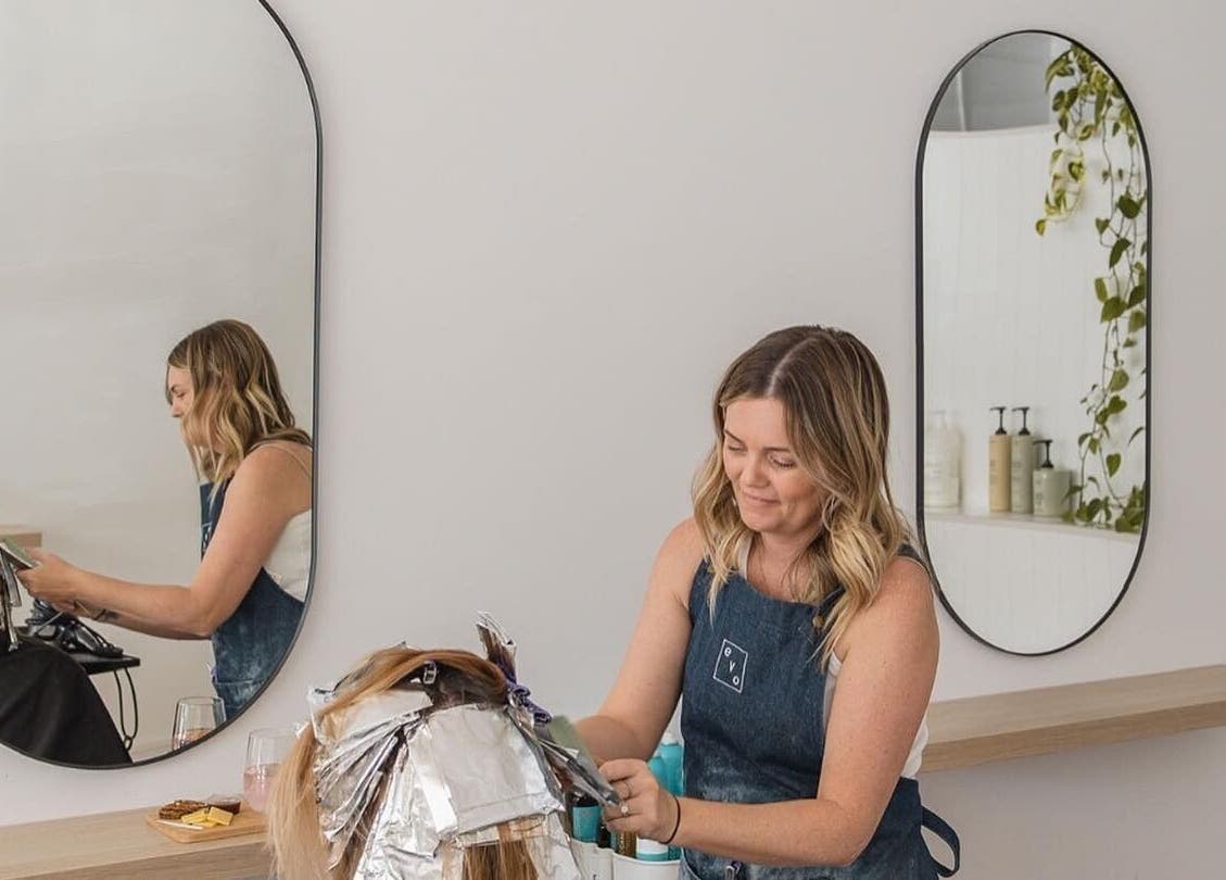 Stylist foiling hair at Stellar Salon, Coolangatta, Queensland, AU with mirrors and plant decor.