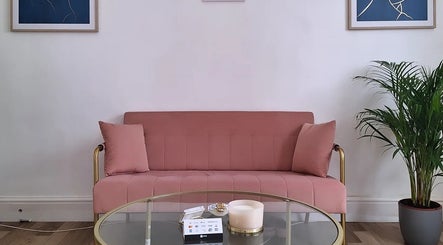 Chic pink sofa in Perfect-ink Beauty lounge, Hereford, England, GB with art and plant decor.