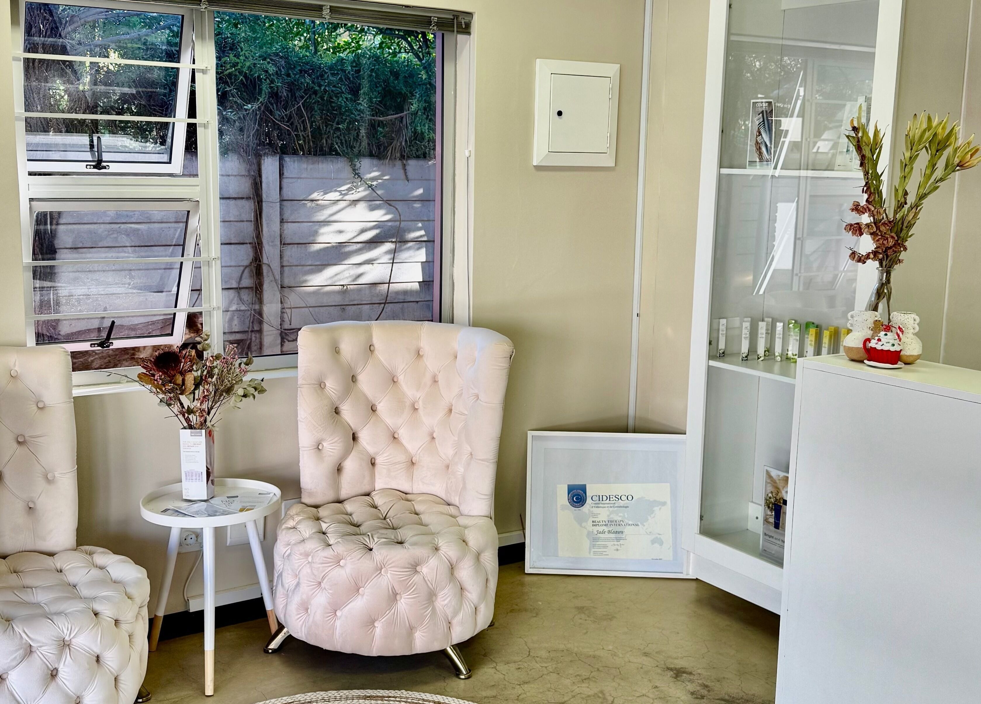 Elegant seating area at Aura Beauty & Wellness, Windhoek, Khomas Region, NA with plush chairs and greenery.