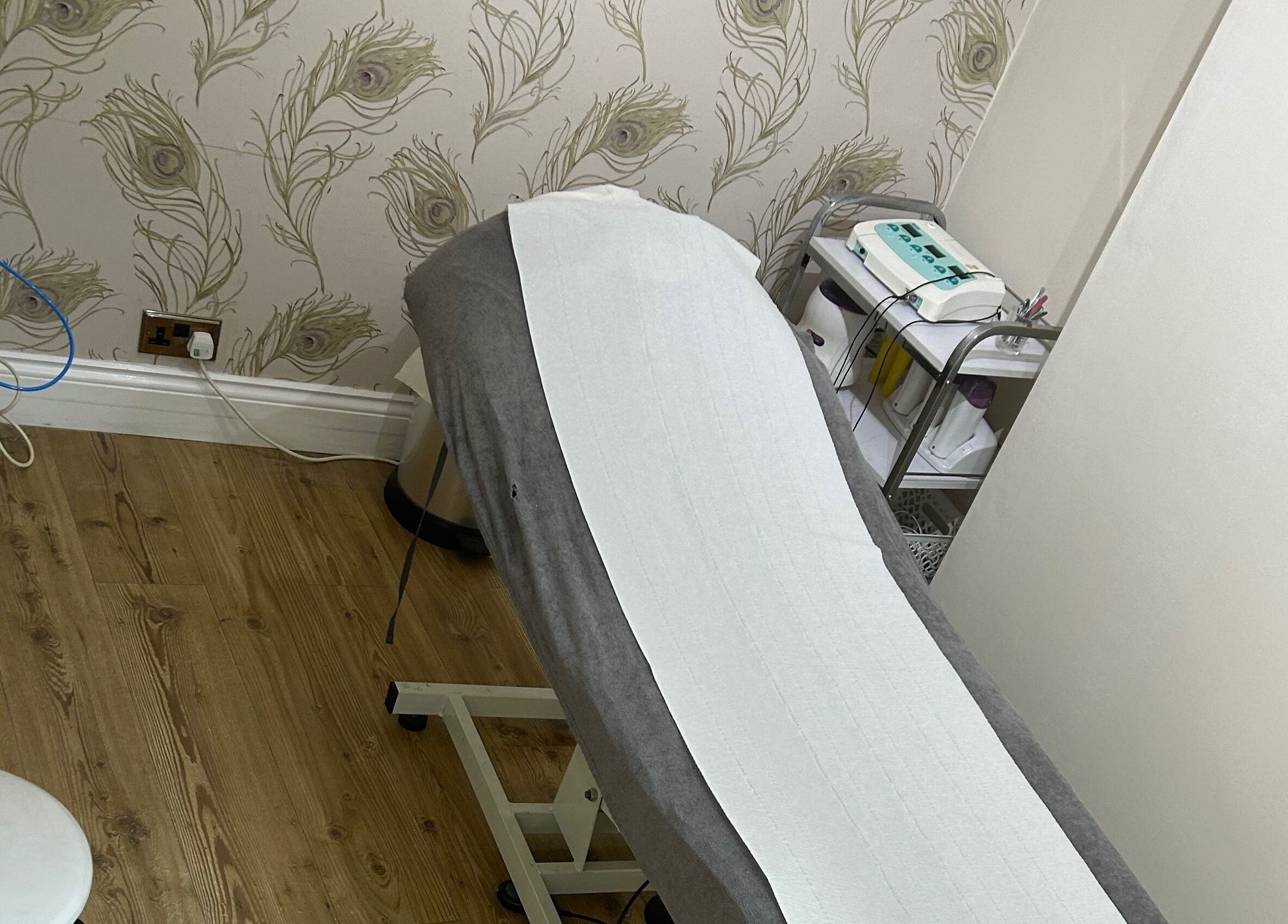 Treatment room at Beauty Worx in Taunton, England, featuring a comfortable massage table and elegant decor.