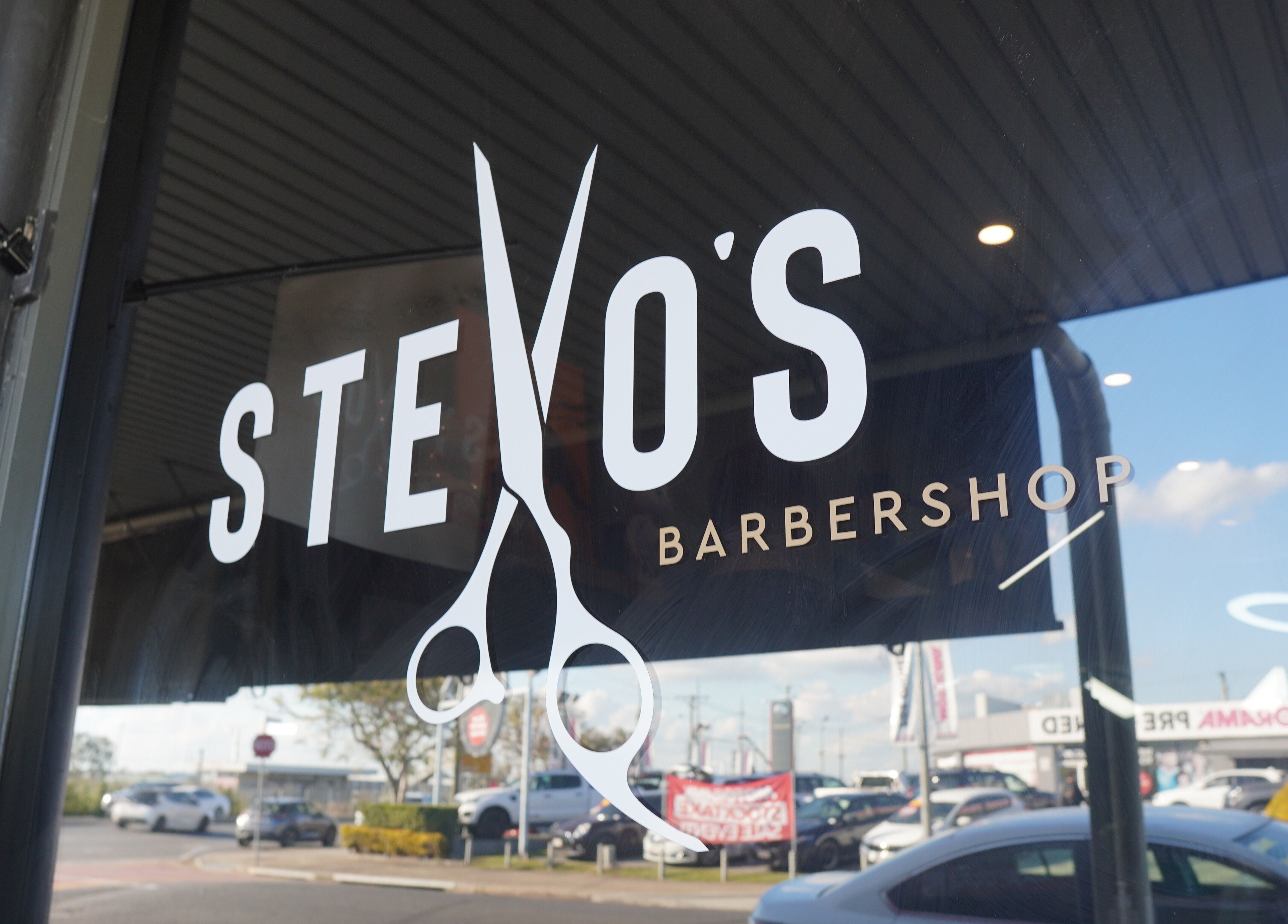 Stevo’s Barbershop window display in Moorooka, Queensland, AU featuring a scissors-themed logo.