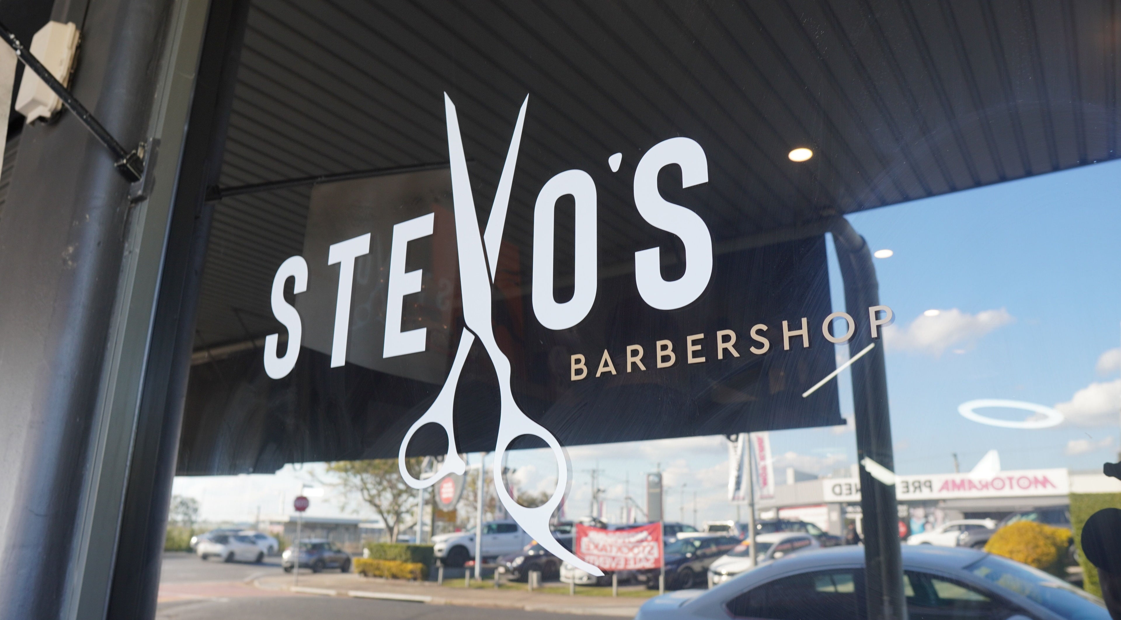 Stevo’s Barbershop window display in Moorooka, Queensland, AU featuring a scissors-themed logo.