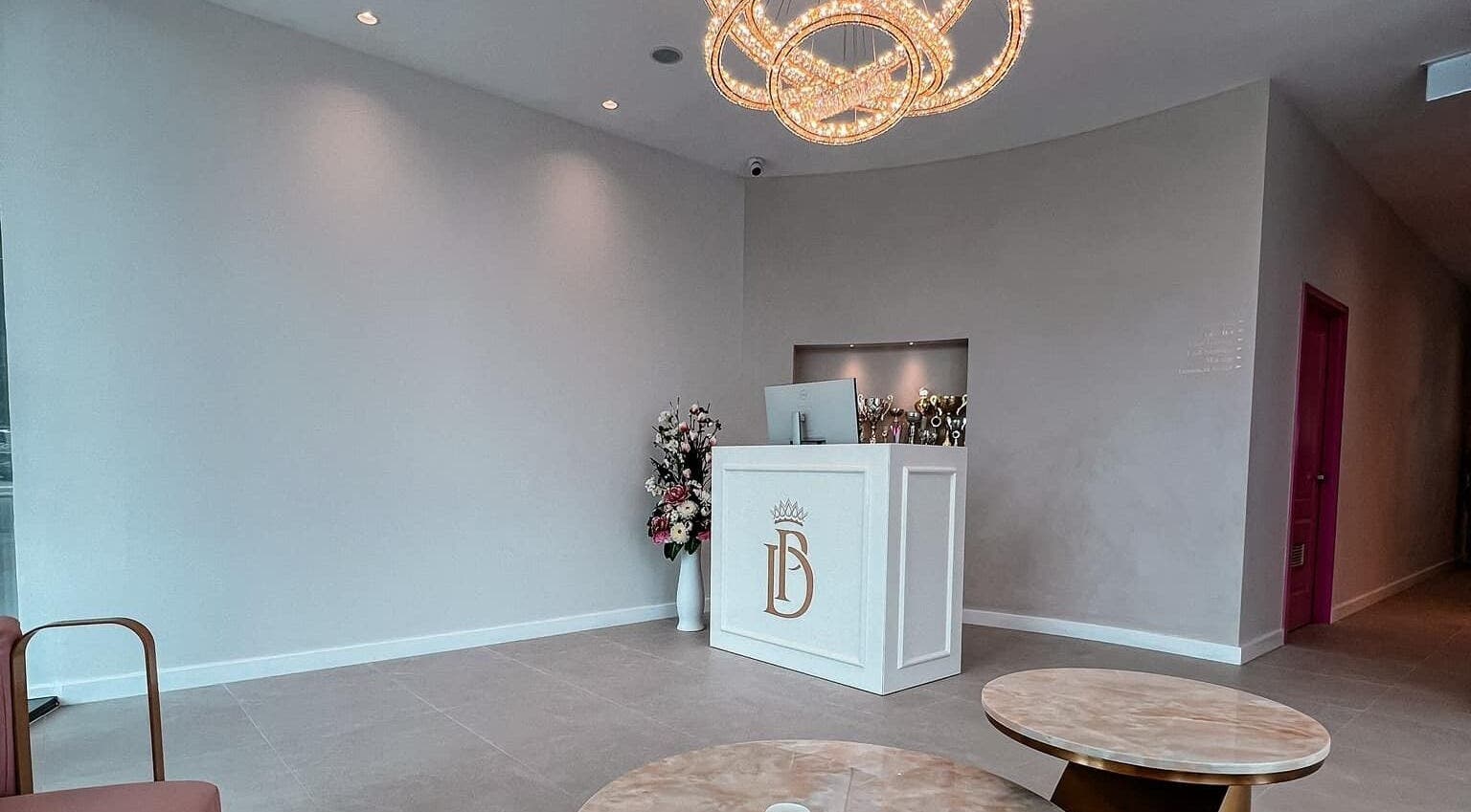 Reception area at All About You BodySculpting Perth in Mount Pleasant, WA, featuring a chic chandelier and floral decor.